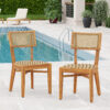 Acacia wood and light brown plastic rattan dining chairs beside a swimming pool.