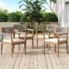 Four acacia and rope dining armchairs with cream seat cushions arranged on a wooden deck.