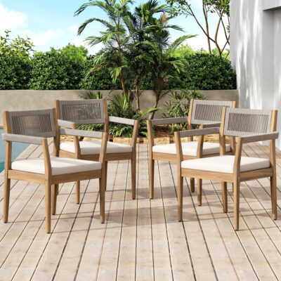 Four acacia and rope dining armchairs with cream seat cushions arranged on a wooden deck.