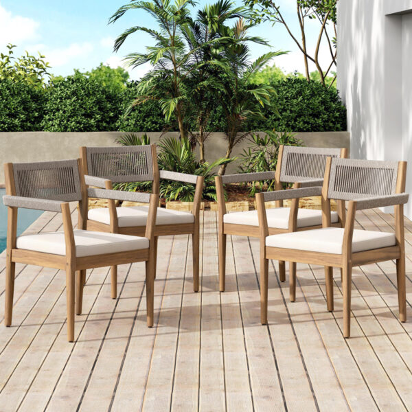 Four acacia and rope dining armchairs with cream seat cushions arranged on a wooden deck.
