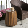 Brown Tree-Stump Side Table – Woven Seating Tree-stump side table with a brown wood-grain finish beside woven seating