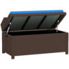 Brown wicker storage bench with its cushioned lid open, showing the interior compartment and a blue seat cushion.