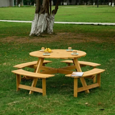Natural Wood Round Picnic Table – Four Built-In Benches Natural wood round picnic table with four attached slatted benches on a lawn.