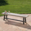 Light gray slatted acacia bench with a black metal frame on a stone patio