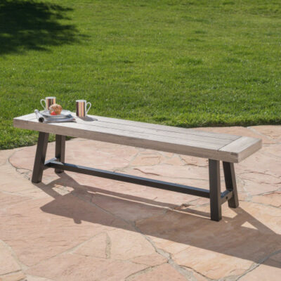 Light gray slatted acacia bench with a black metal frame on a stone patio